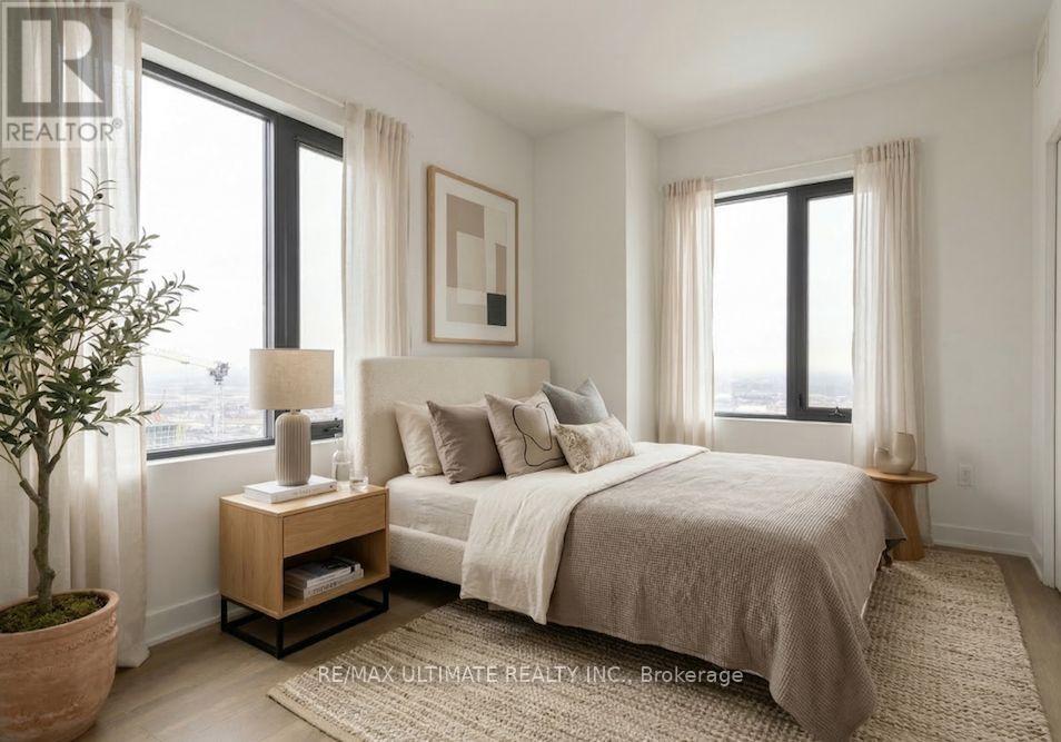 A bedroom with a large bed, a nightstand with a lamp, and a potted plant.