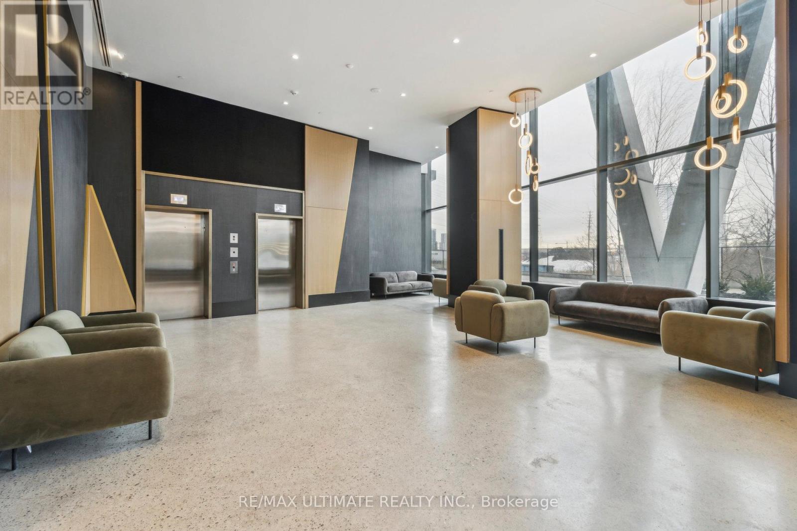 A spacious lobby with a glass wall and a row of brown couches.