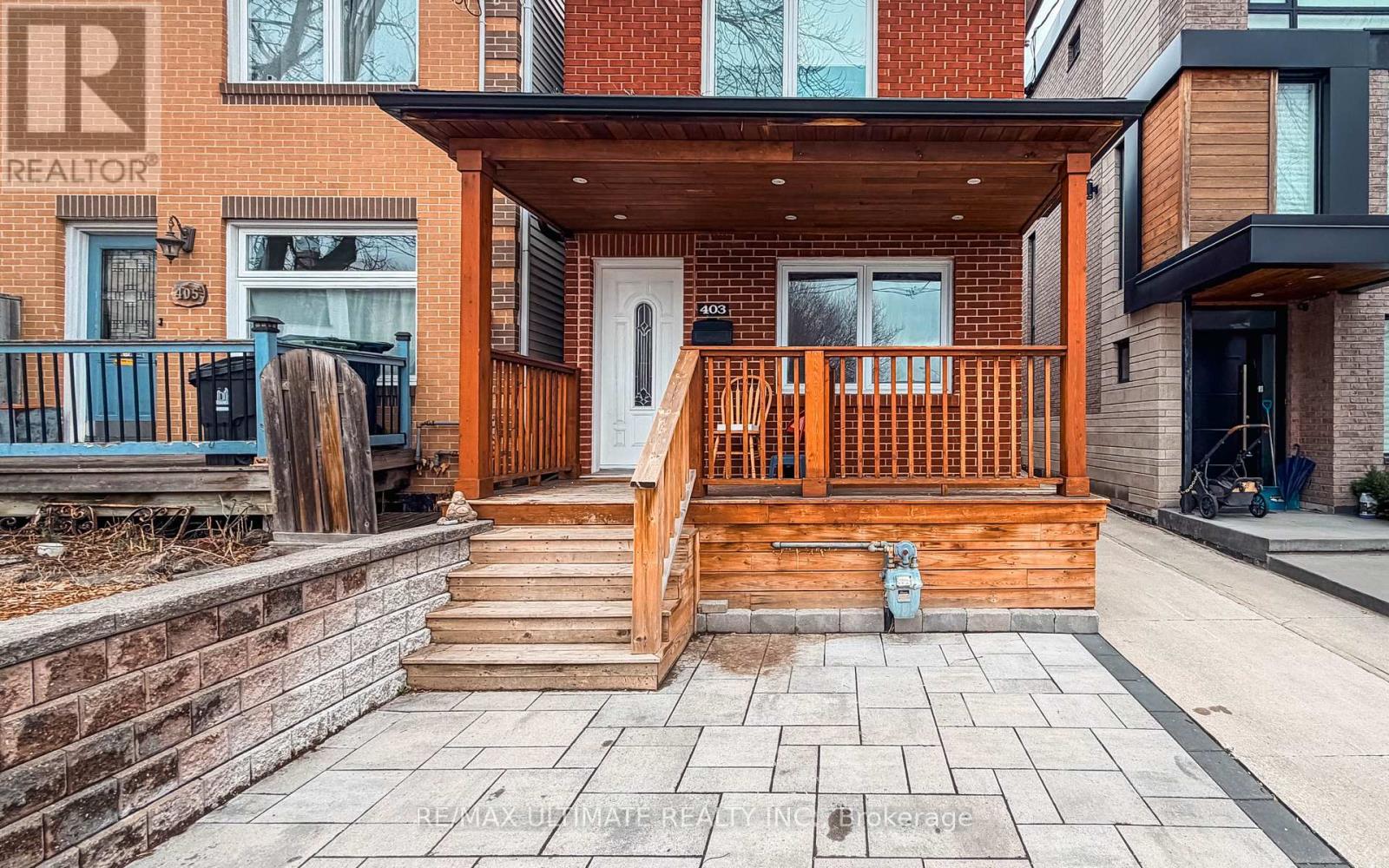 A wooden deck with a white door and a brick wall with a REALTOR sign.