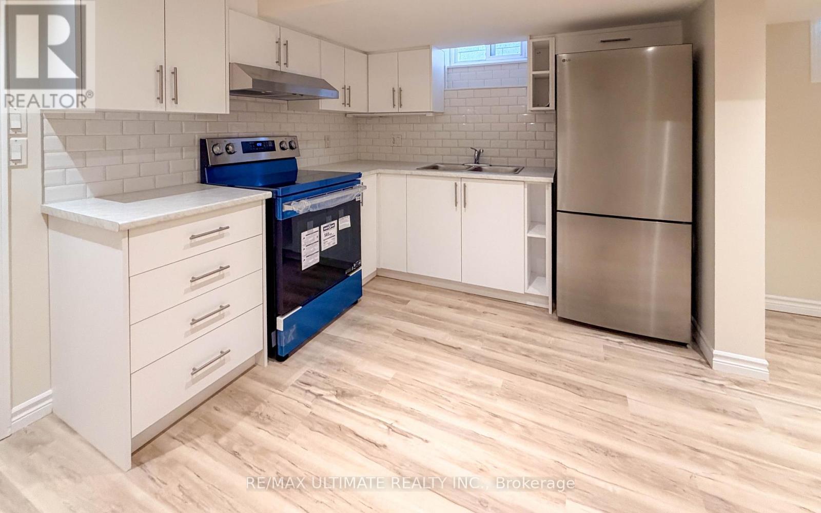 A kitchen with white cabinets and a stainless steel refrigerator.