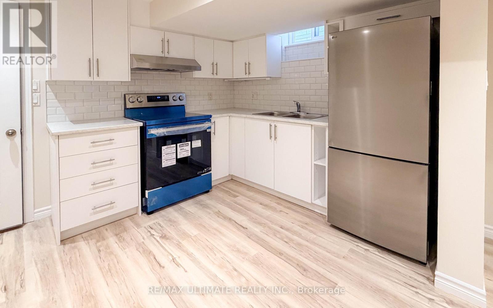 A kitchen with a refrigerator, sink, and cabinets.