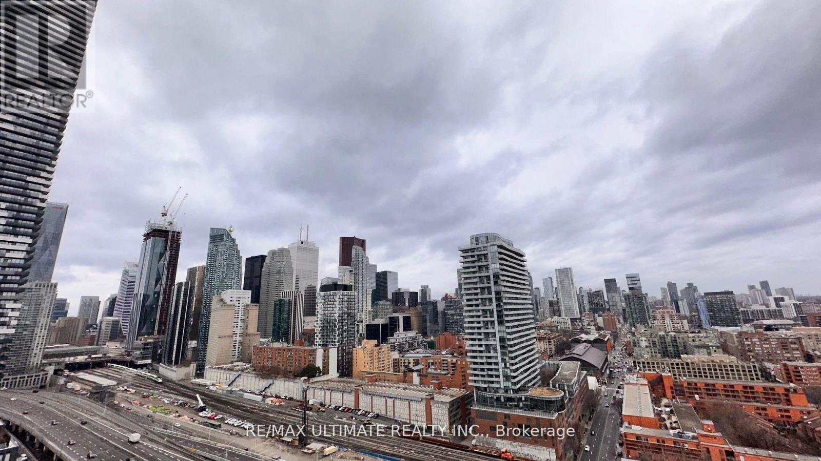 A cityscape with a cloudy sky and a highway in the foreground.