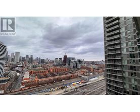 A cityscape with a tall building on the right and a train on the tracks in the middle.