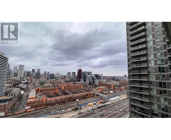 A cityscape with a tall building on the right and a train on the tracks in the middle.