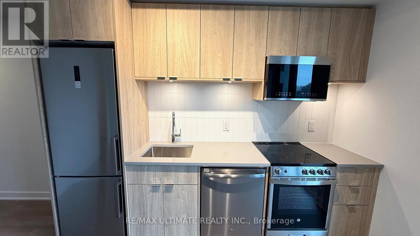 A kitchen with wooden cabinets and a black fridge.