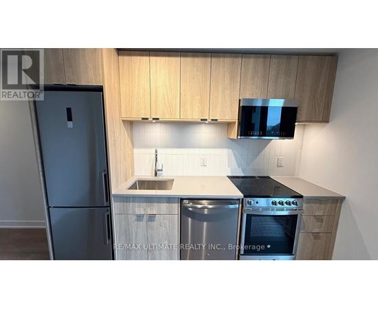 A kitchen with wooden cabinets and a black fridge.