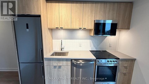 A kitchen with wooden cabinets and a black fridge.