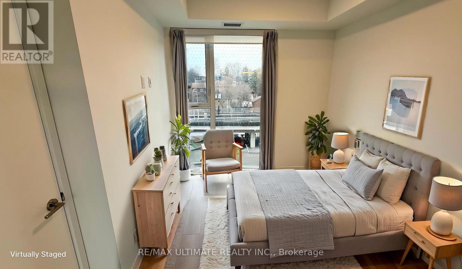 A bedroom with a large bed, a chair, and a window overlooking a cityscape.