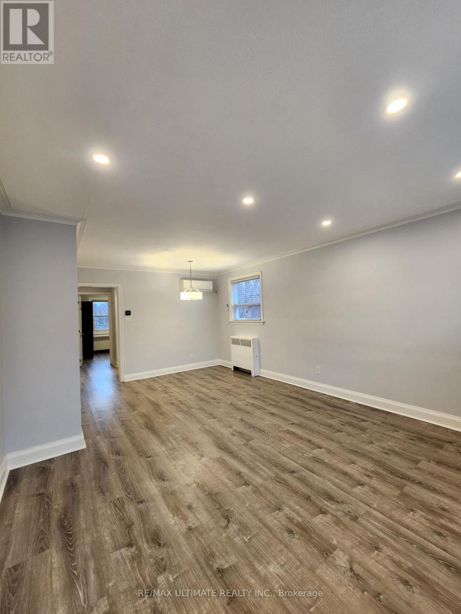 A spacious room with wooden flooring and white walls.