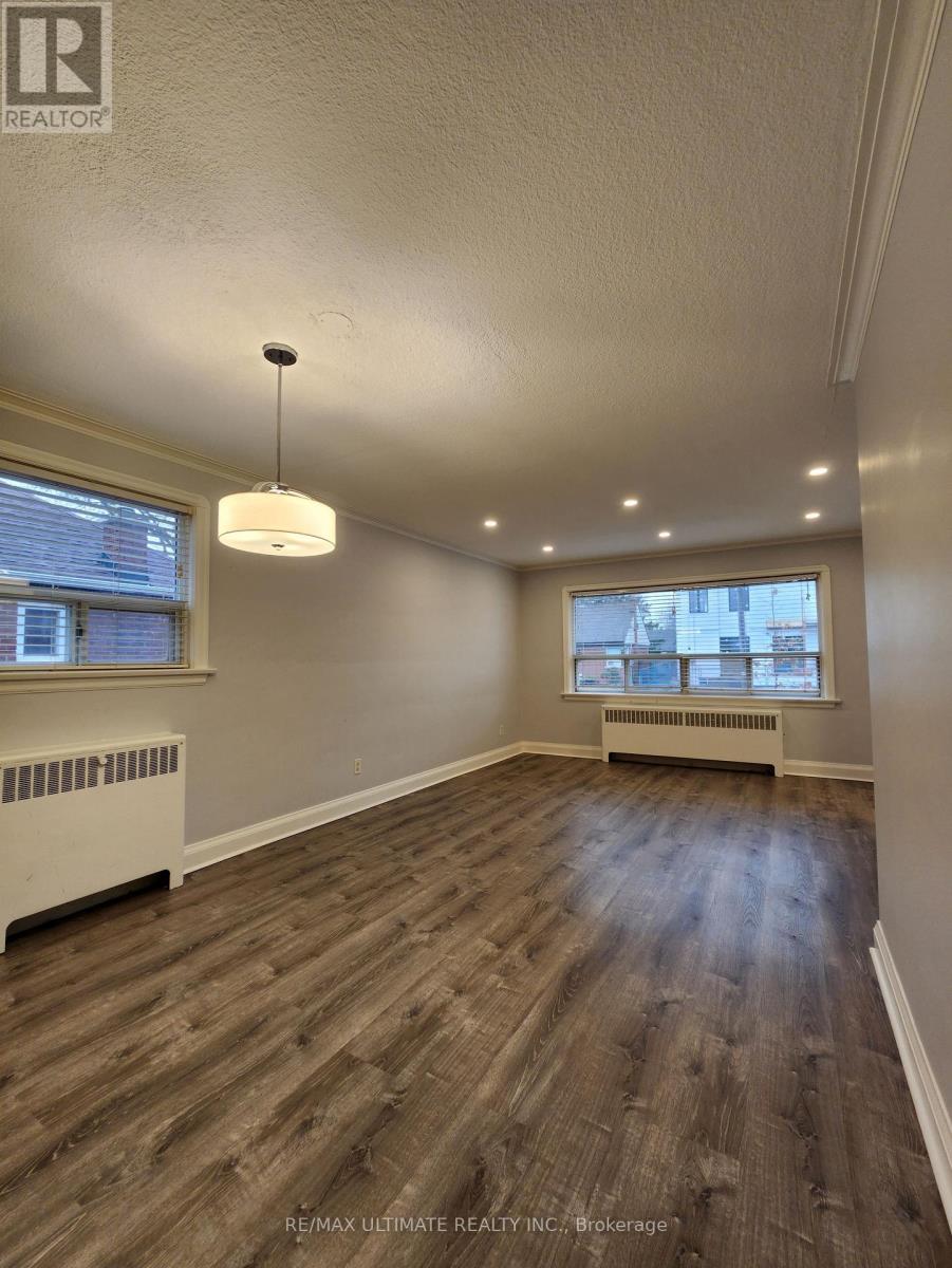 A large empty room with wood flooring and a window.