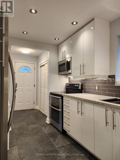 A modern kitchen with white cabinets and a black stove top oven.