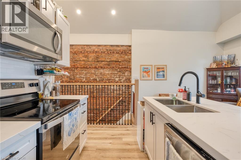 A kitchen with a stove top oven and a brick wall.