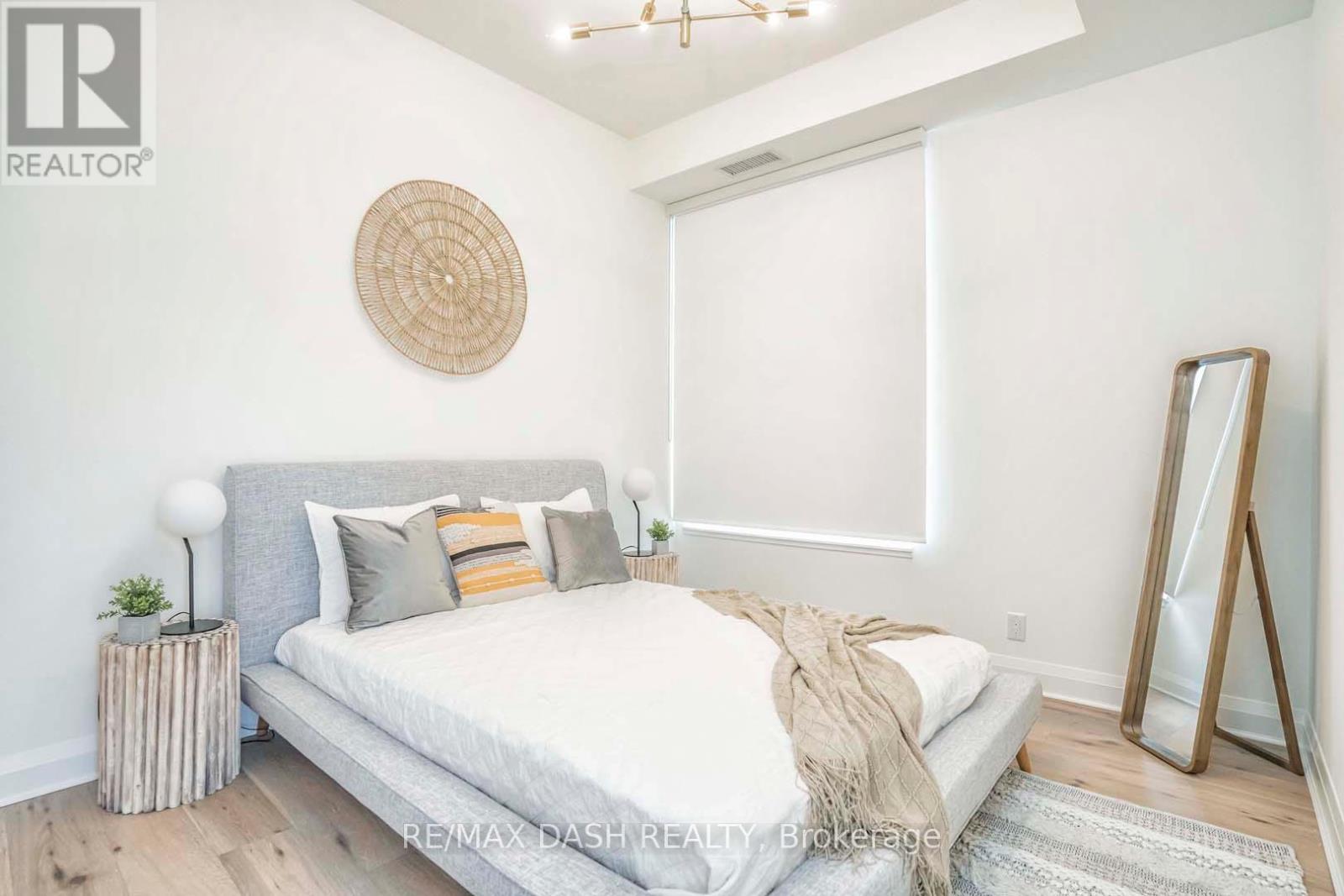 A bedroom with a bed, pillows, a mirror, and a rug.