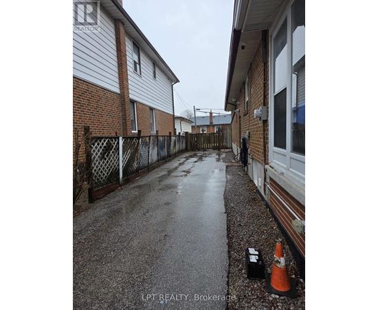 A wet residential street with a traffic cone and a black box on the ground.