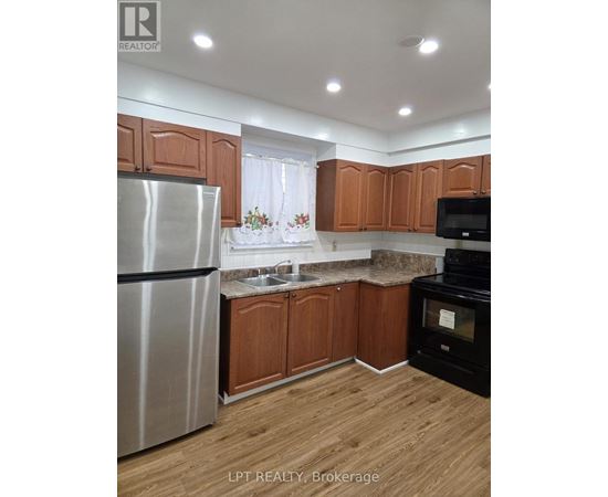 A kitchen with wooden cabinets and a stainless steel refrigerator.