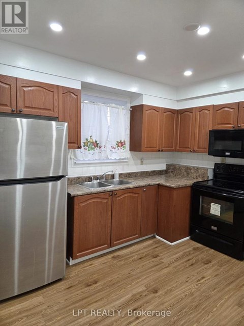 A kitchen with wooden cabinets and a stainless steel refrigerator.