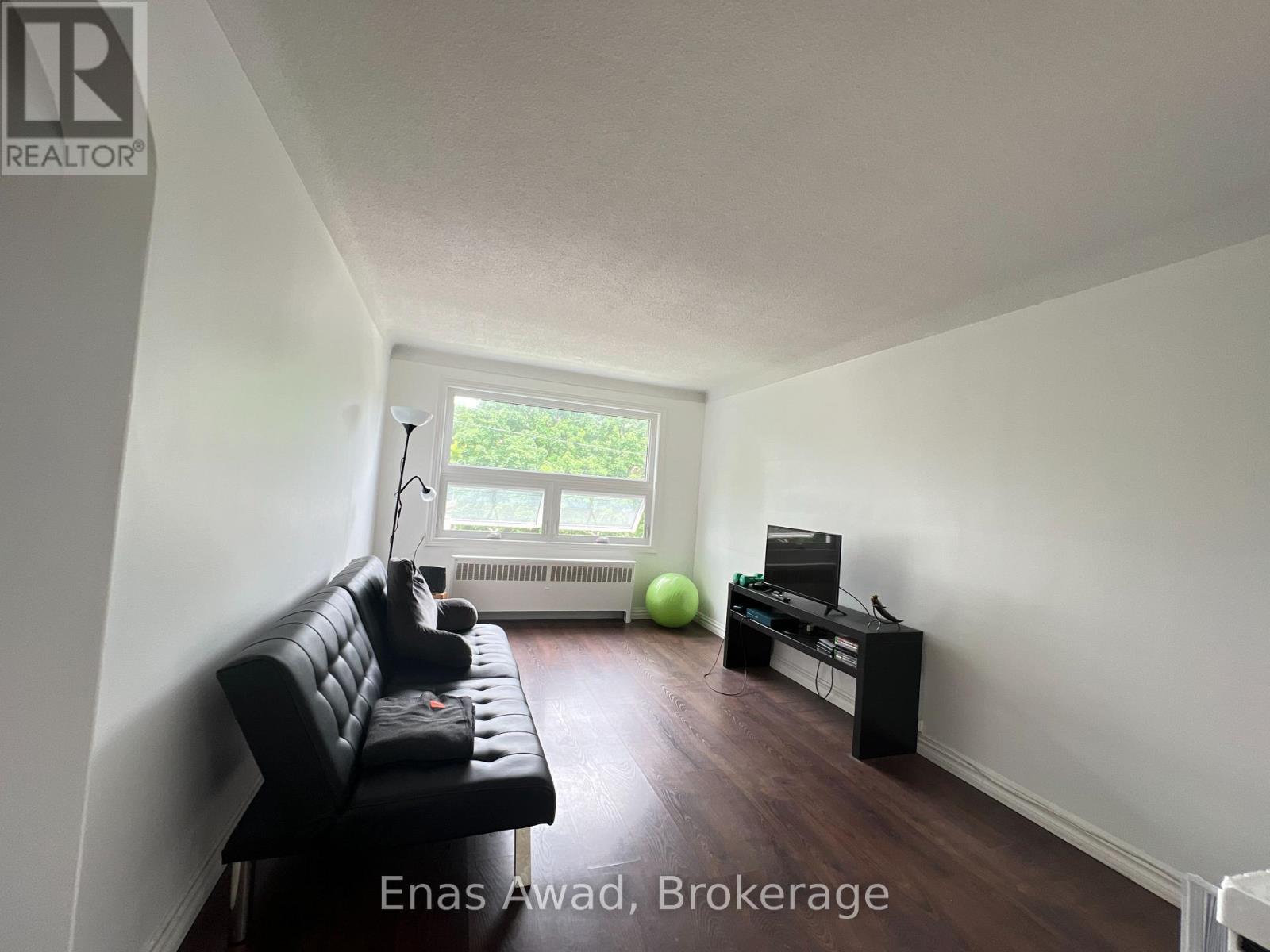 A living room with a black leather sofa and a green exercise ball.