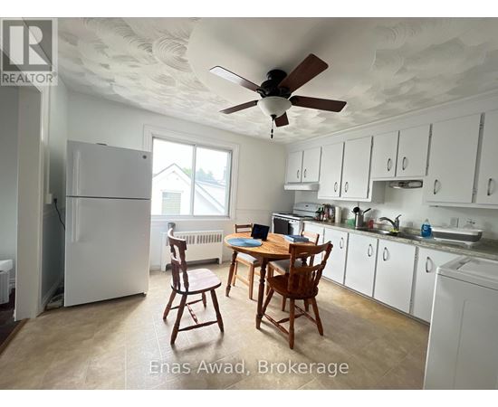 A kitchen with white cabinets and a table with chairs.