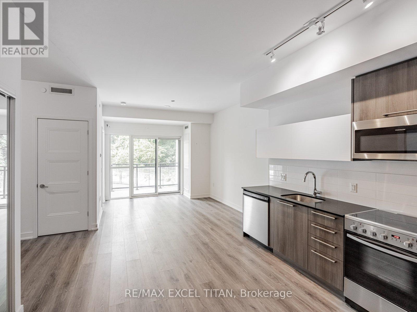 A modern kitchen with wooden floors and stainless steel appliances.
