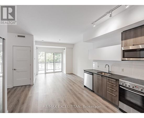 A modern kitchen with wooden floors and stainless steel appliances.