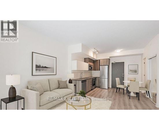 A well-lit, modern living room with a grey sofa, a dining table set for four, and a kitchen area in the background.