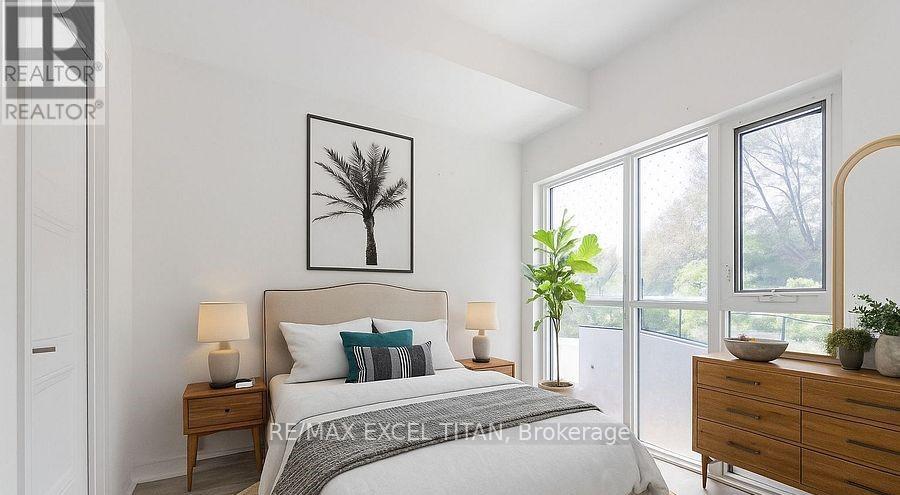 A bedroom with a large bed, a nightstand with a lamp, a dresser with a mirror, and a framed picture of a tree on the wall.