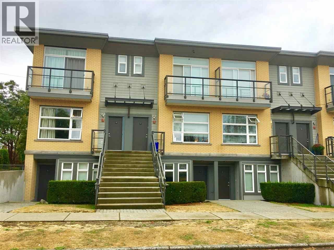A two-story apartment building with a balcony on the second floor.