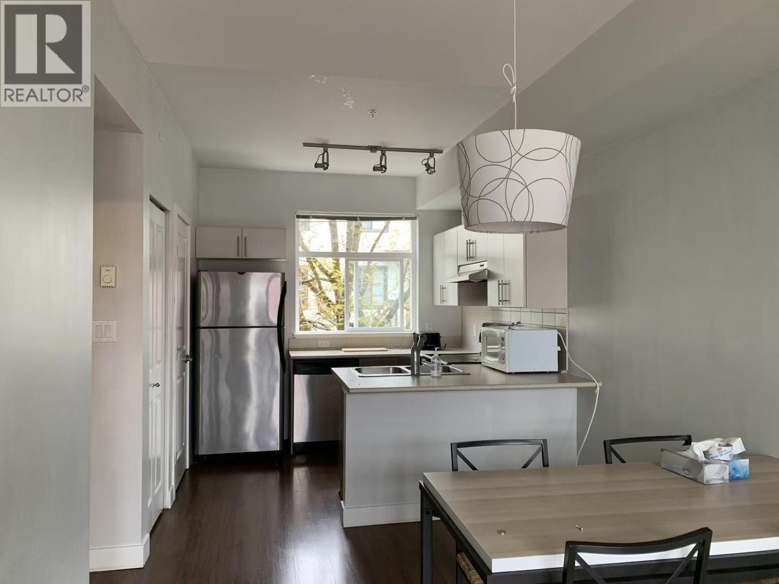 A kitchen with a refrigerator, microwave, and oven.