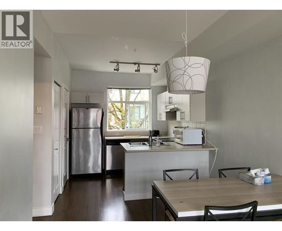 A kitchen with a refrigerator, microwave, and oven.