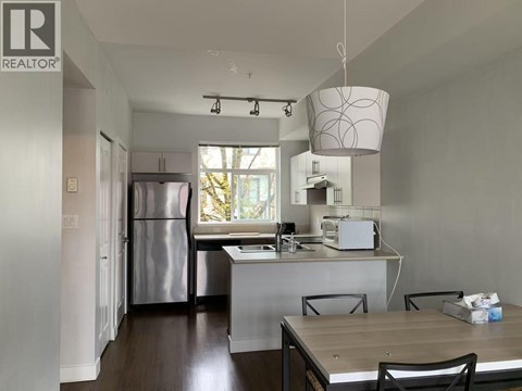 A kitchen with a refrigerator, microwave, and oven.