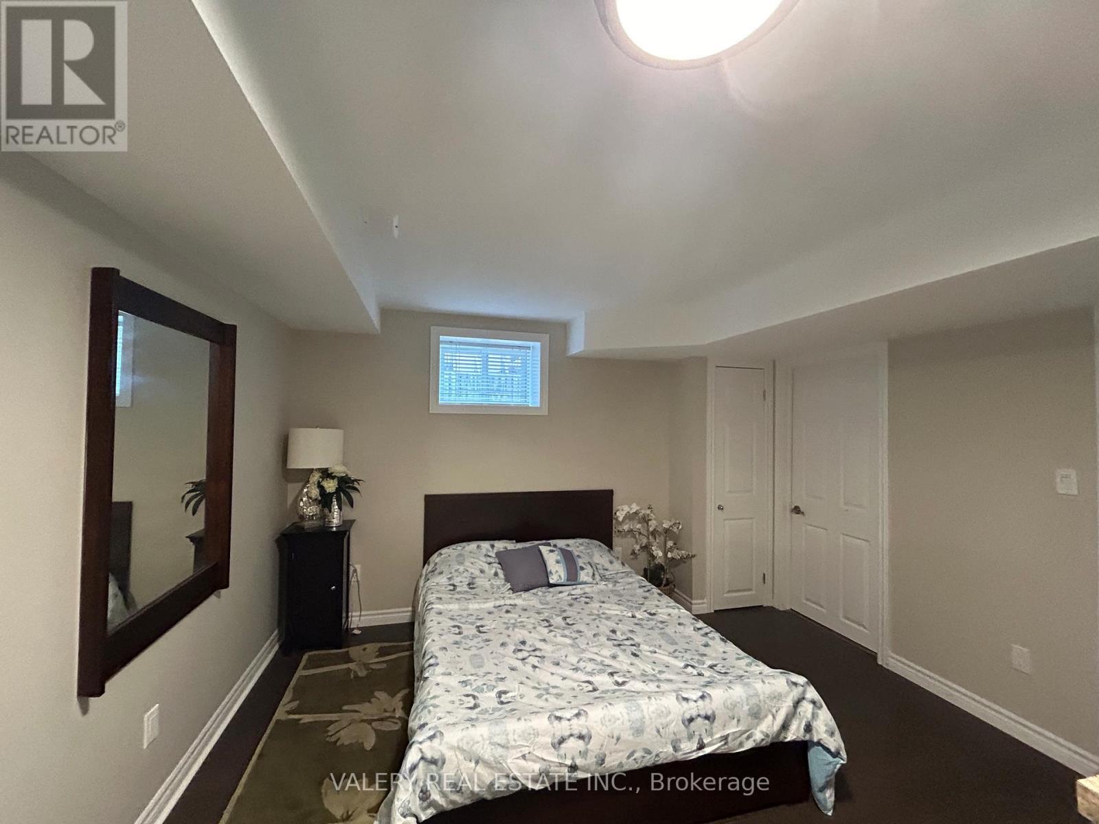 A bedroom with a bed, nightstand, and mirror.