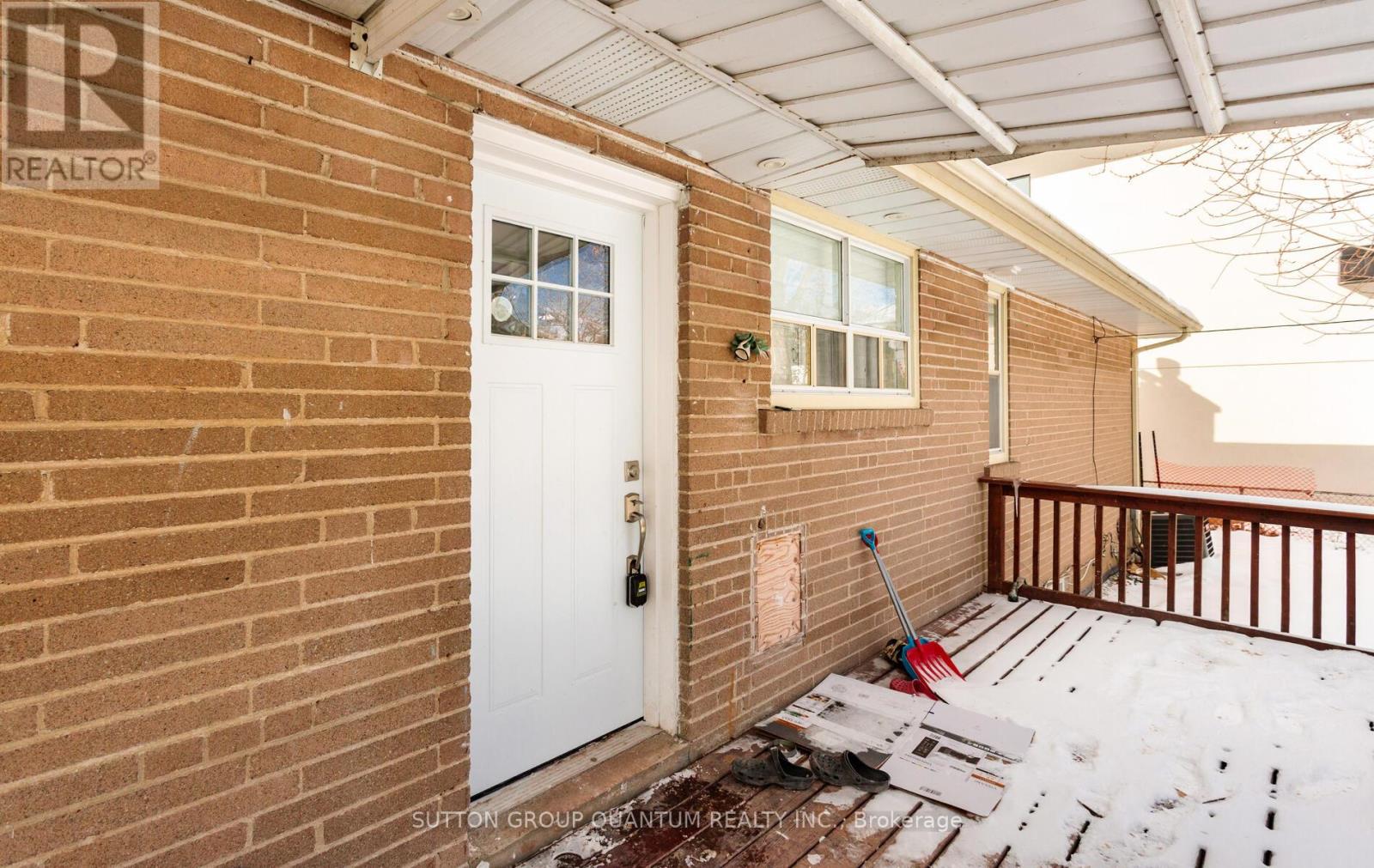 A white door is on a brick wall with a sign that says REALTOR.