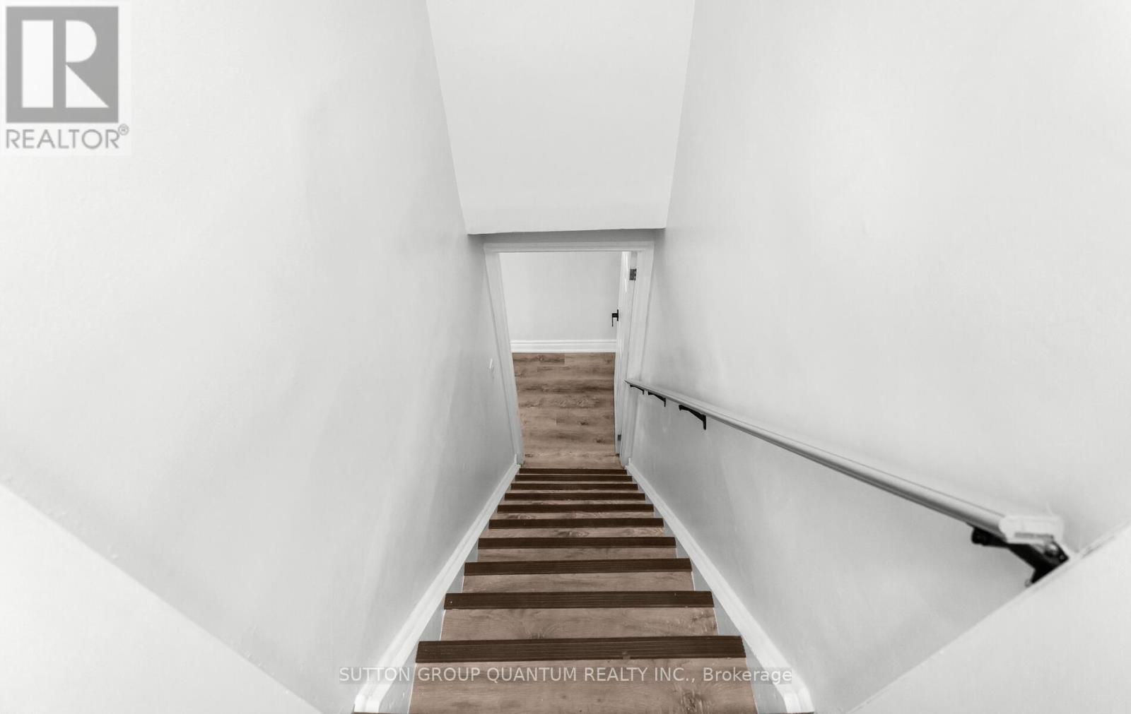 A stairway with a wooden handrail and white walls.