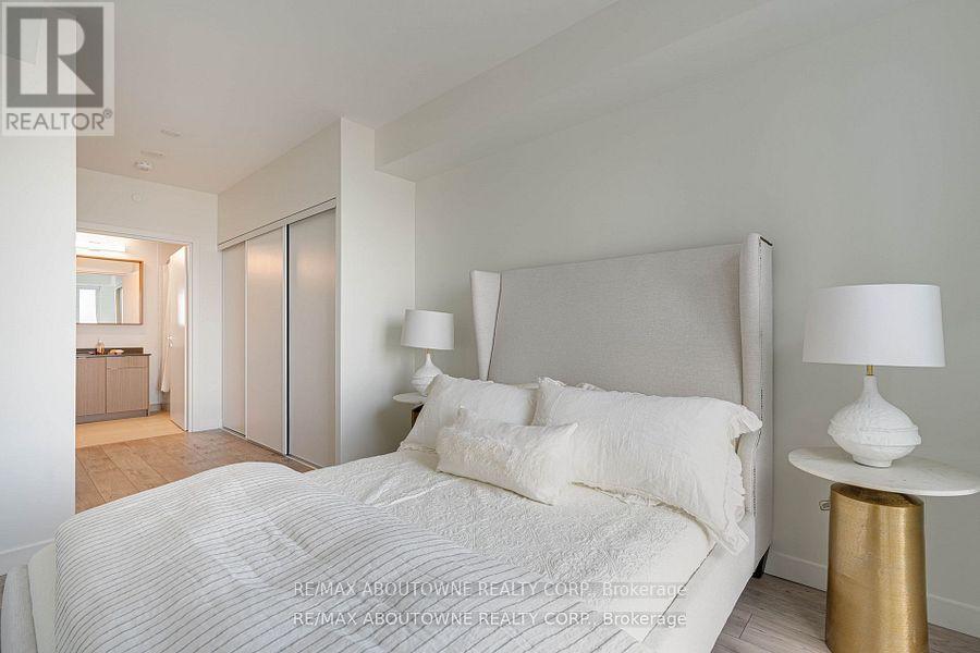 A bedroom with a large bed and a lamp on a side table.