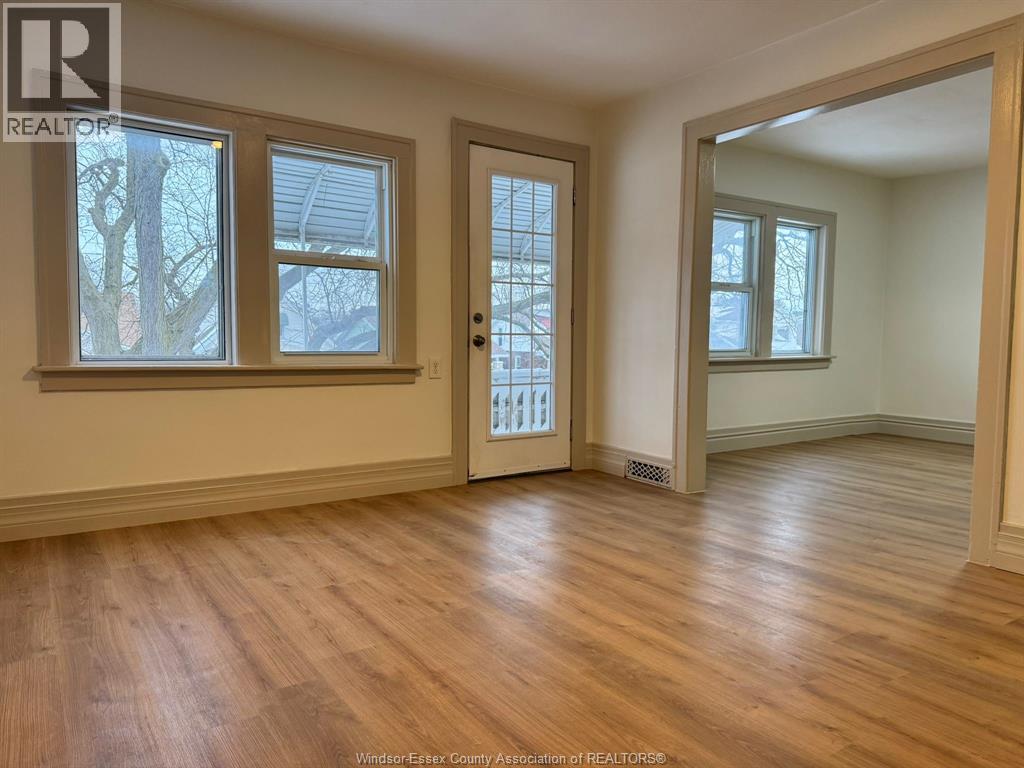 A room with wooden floors and a door leading to another room.