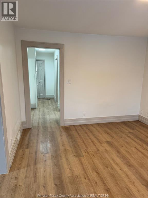 A room with wooden flooring and a doorway leading to another room.