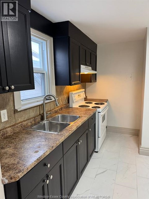 A kitchen with black cabinets and a white stove top oven.