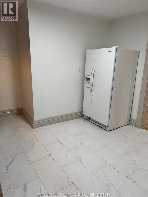 A white refrigerator in a room with a tile floor.