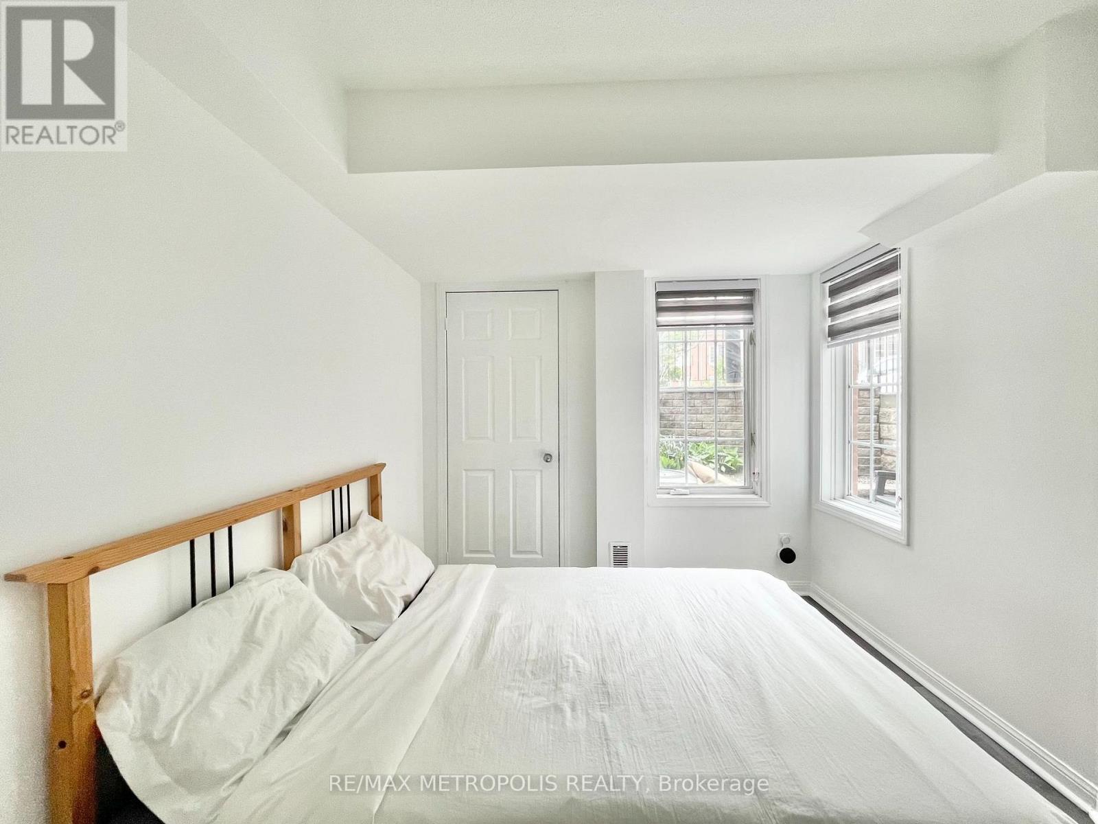 A bedroom with a bed, pillows, and a window.