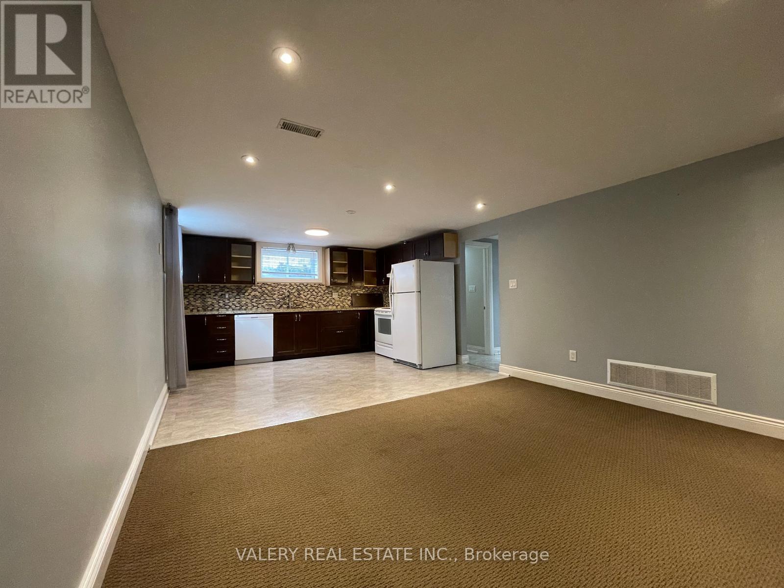 A spacious room with a kitchenette and a window.