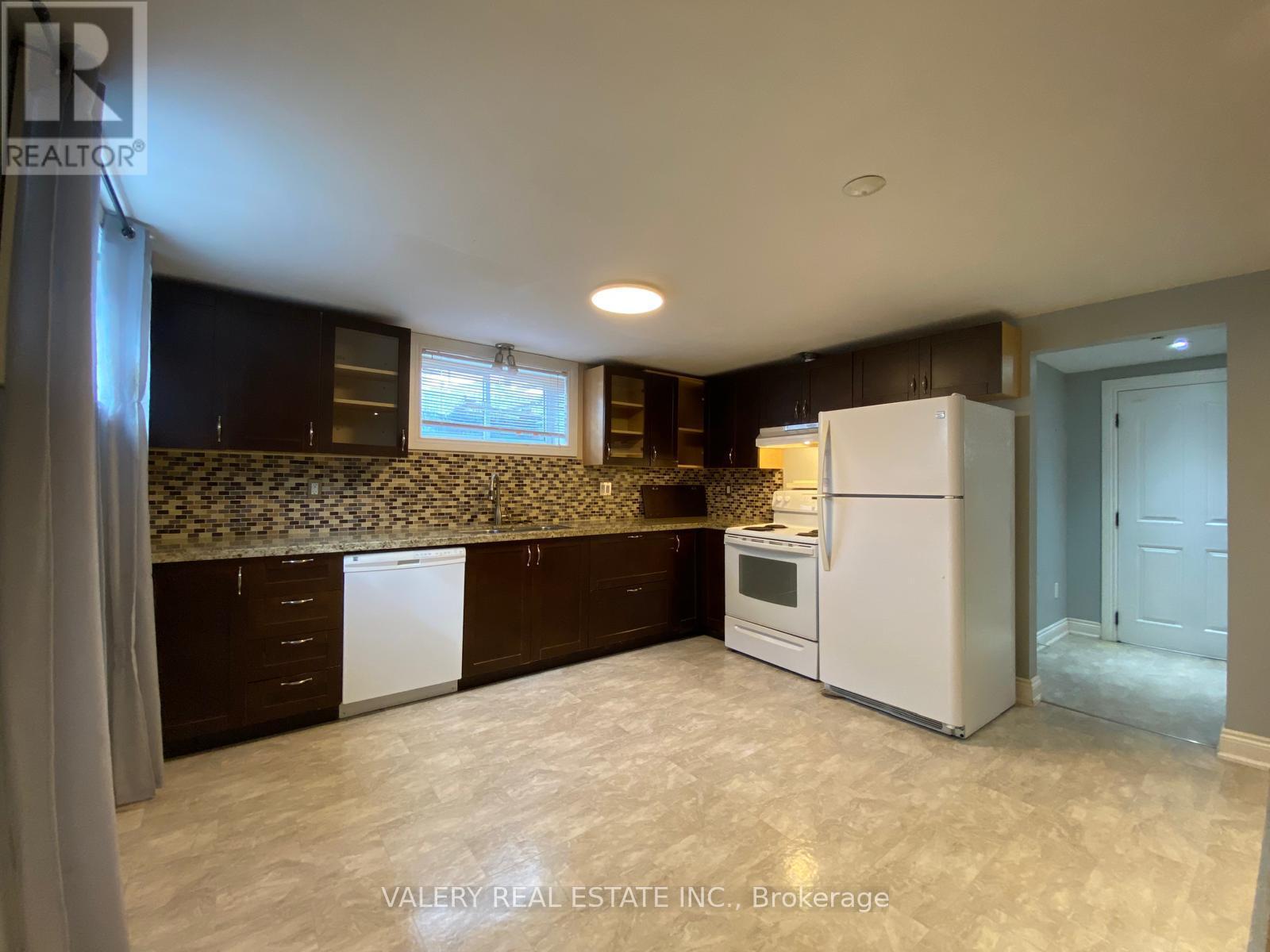 A kitchen with white appliances and a marble backsplash.