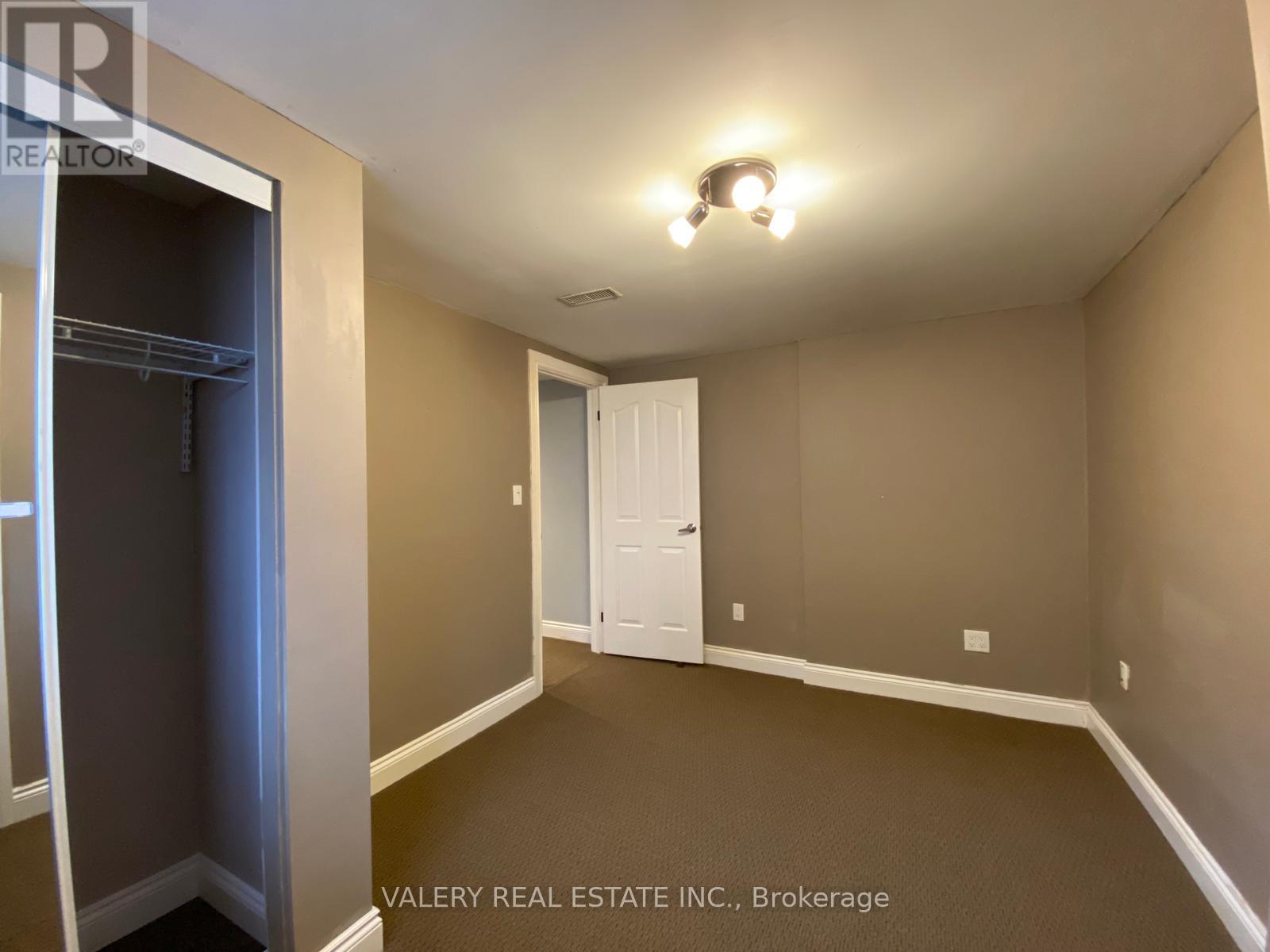 A spacious room with a white door and a light on the ceiling.
