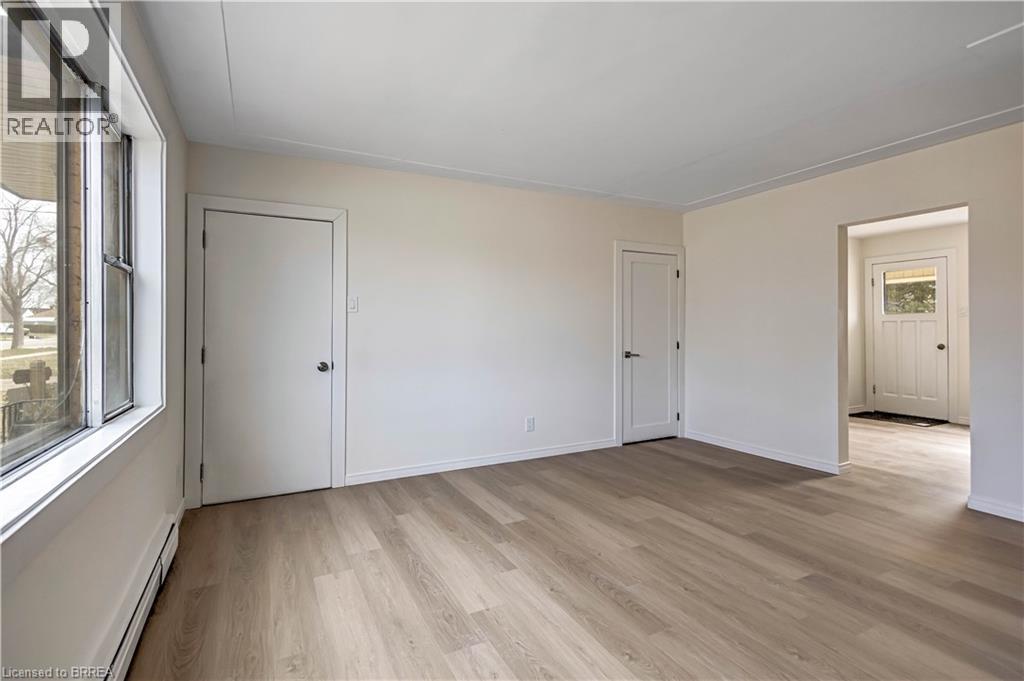 A room with wooden floors and white walls, with a window on the left side.