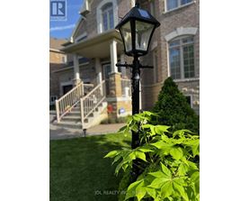 A black street lamp stands in front of a house with a well-manicured lawn.