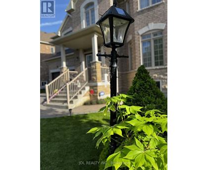 A black street lamp stands in front of a house with a well-manicured lawn.