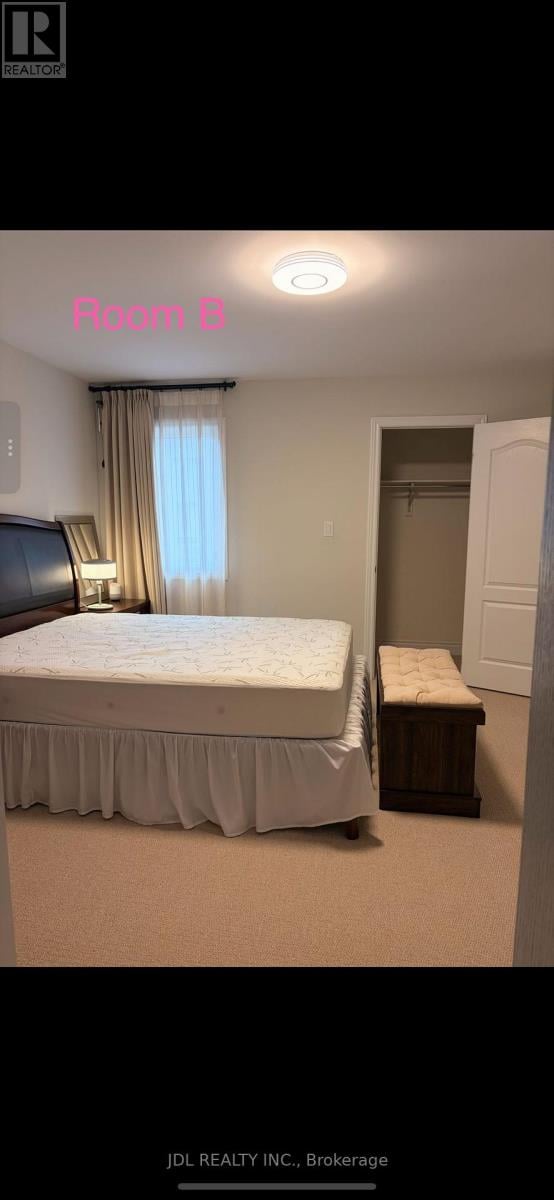 A bedroom with a bed, nightstand, and window.