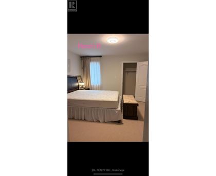 A bedroom with a bed, nightstand, and window.