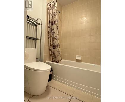 A white toilet sits next to a bathtub in a bathroom.