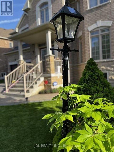 A black street lamp stands in front of a house with a well-manicured lawn.