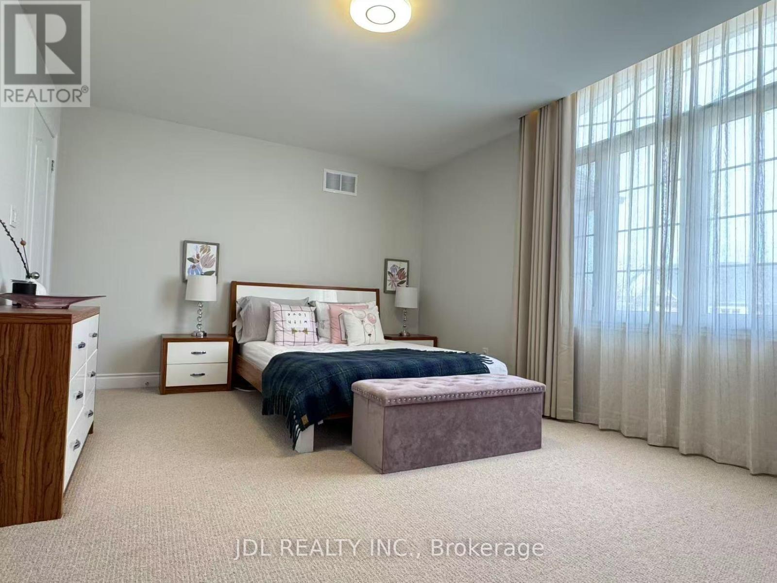 A bedroom with a bed, nightstand, and window with curtains.